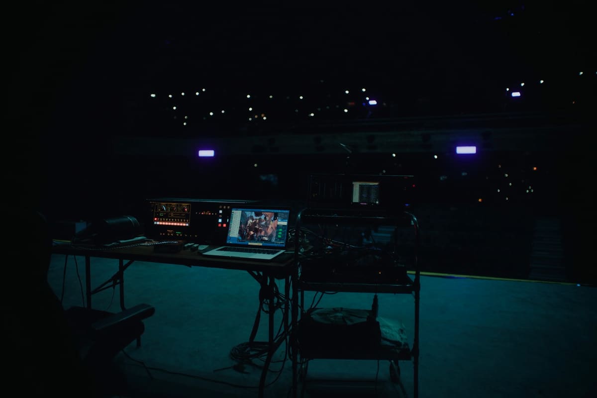 A production position at the back of a darkened auditorium, with a laptop and a console