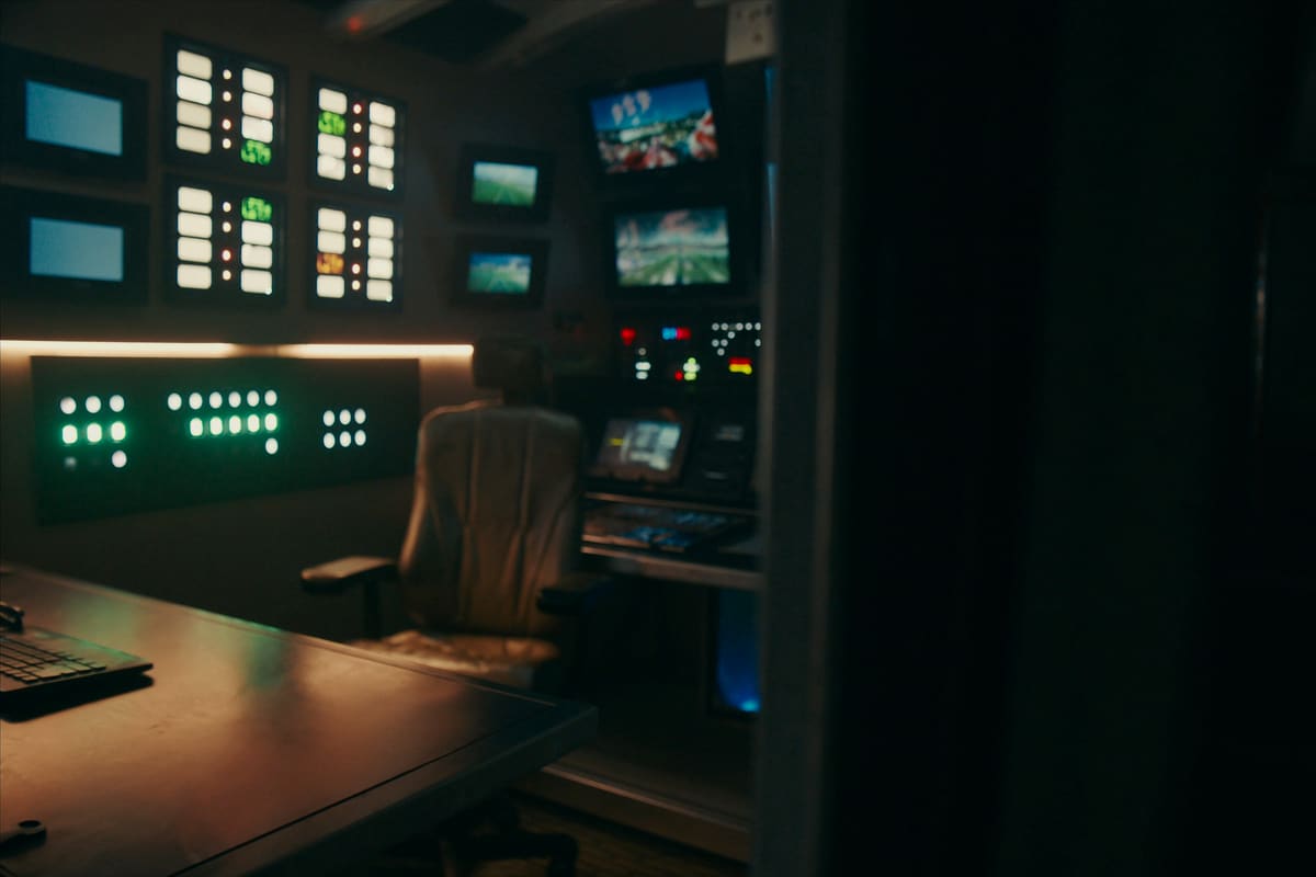 The inside of an outside-broadcast truck at night, monitor gallery lit